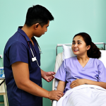 **A physiotherapy student interacting empathetically with a patient in a hospital ward in Malaysia.** The scene should convey a clinical setting with medical equipment visible, but focused on the human connection and care being provided. Include diverse representation of Malaysian patients and healthcare professionals.